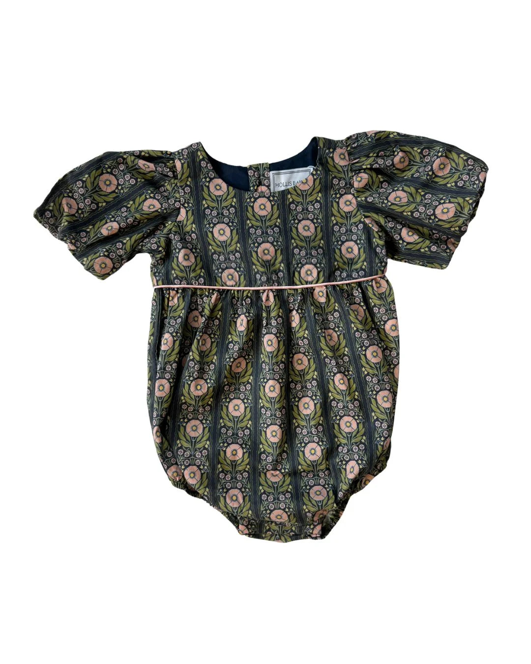 A baby bubble romper with puff sleeves, featuring an all-over floral and paisley print in muted green, pink, and beige tones on a dark background, with a thin pink waist tie.