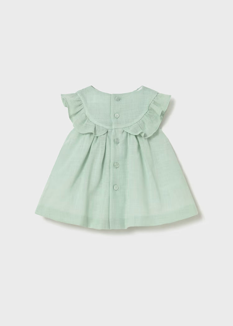 Back of pale green smocked dress with ruffles.