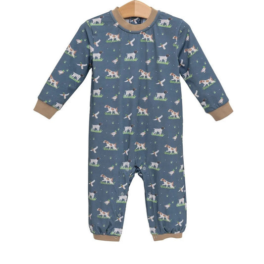 A baby long-sleeve footless one-piece jumpsuit in slate blue, featuring a repeating pattern of dogs and birds, with tan ribbed cuffs and hem.