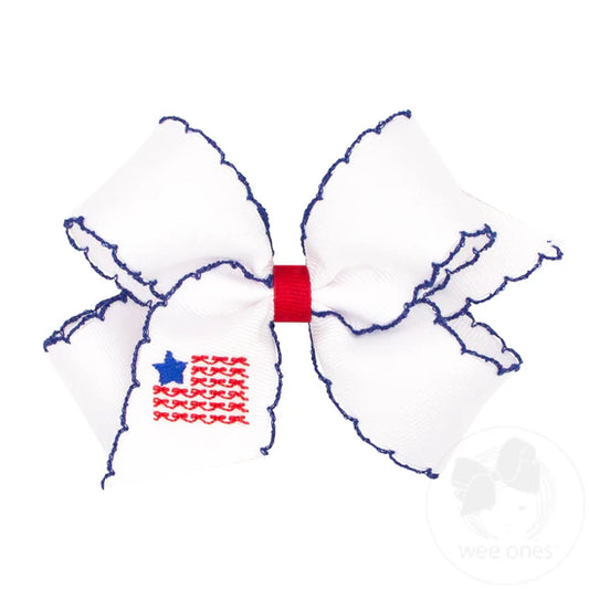 White hair bow with embroidered flag, red center and navy moonstitch edge.