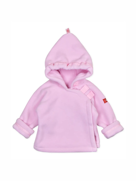 A light pink baby hooded wrap jacket with a plush fleece texture, featuring a small red brand tag on the sleeve and a matching pink drawstring detail on the chest.