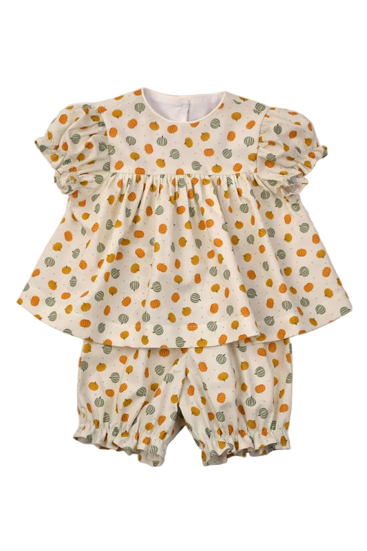 A two-piece baby girl's outfit set consisting of a short-sleeve ruffled peplum top and matching ruffled bloomers, both in an off-white fabric with an orange and green leaf pattern, laid flat on a light gray background.