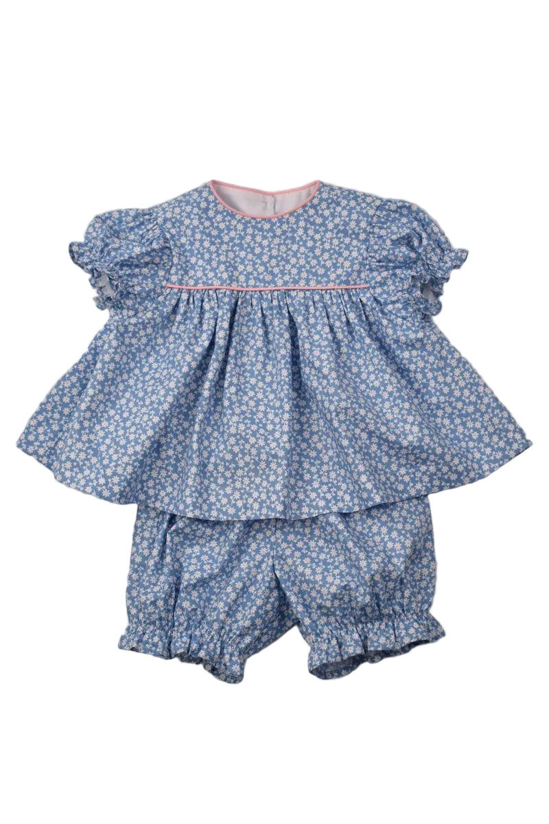 A two-piece baby girl's outfit featuring a blue and white floral print smocked peplum top with flutter sleeves and matching smocked bloomers, laid flat on a neutral gray background.