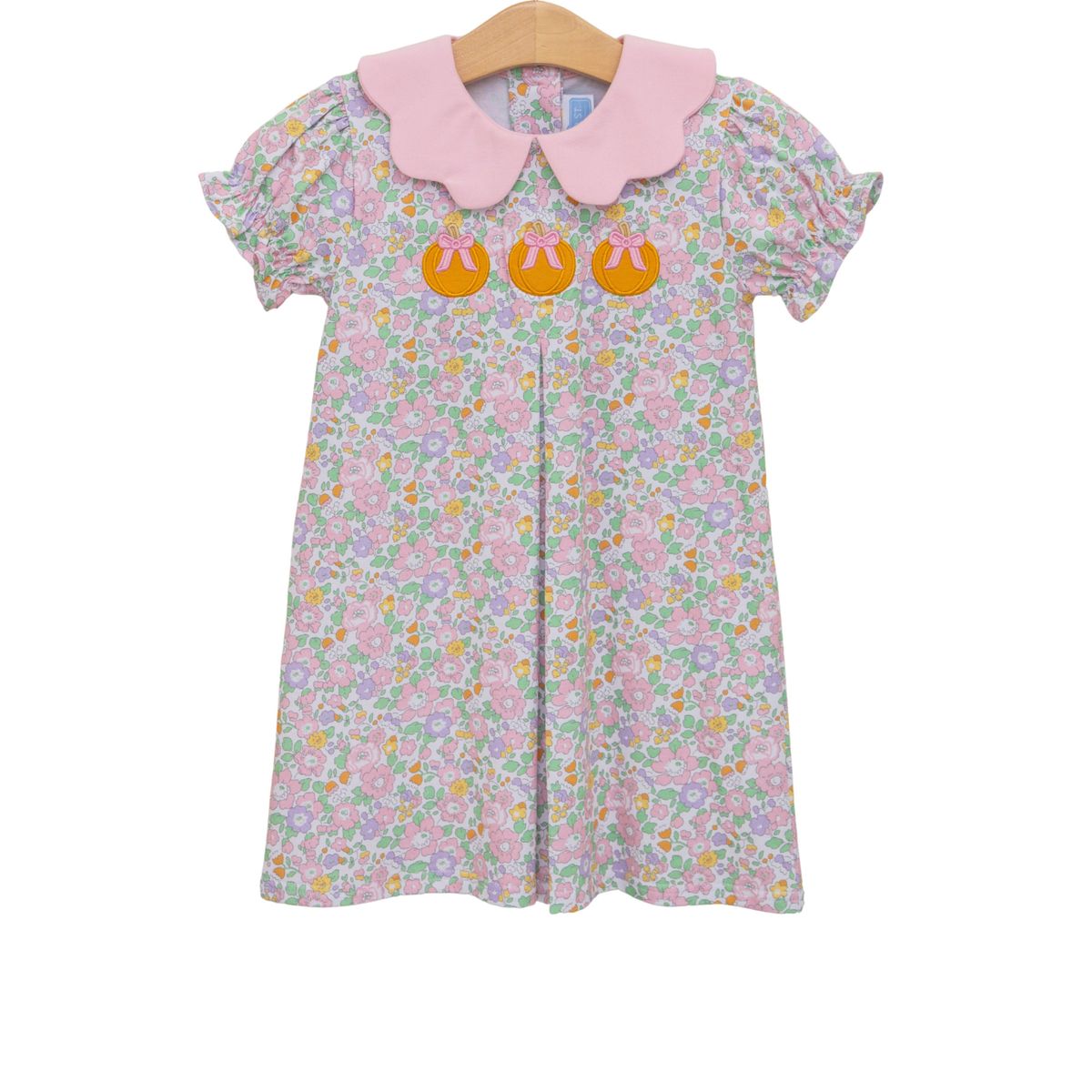 Floral dress with pink collar  and on a hanger against a white background