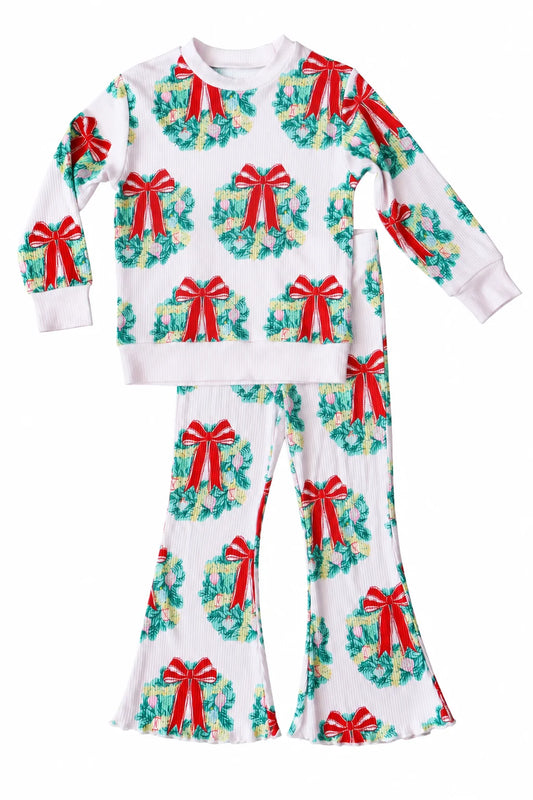 A two-piece children's longe set featuring a long-sleeve top and matching flared pants, printed with a festive Christmas wreath pattern on a white background. Each wreath is decorated with green foliage, yellow accents, and a red bow.