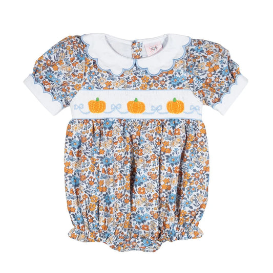A baby girl's short-sleeve bubble romper dress featuring a white Peter Pan collar, a smocked bodice with three orange pumpkins and blue bows, and a blue, orange, and white floral print.