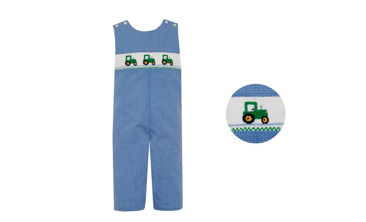 Blue overalls with smocked green tractor design on a white background