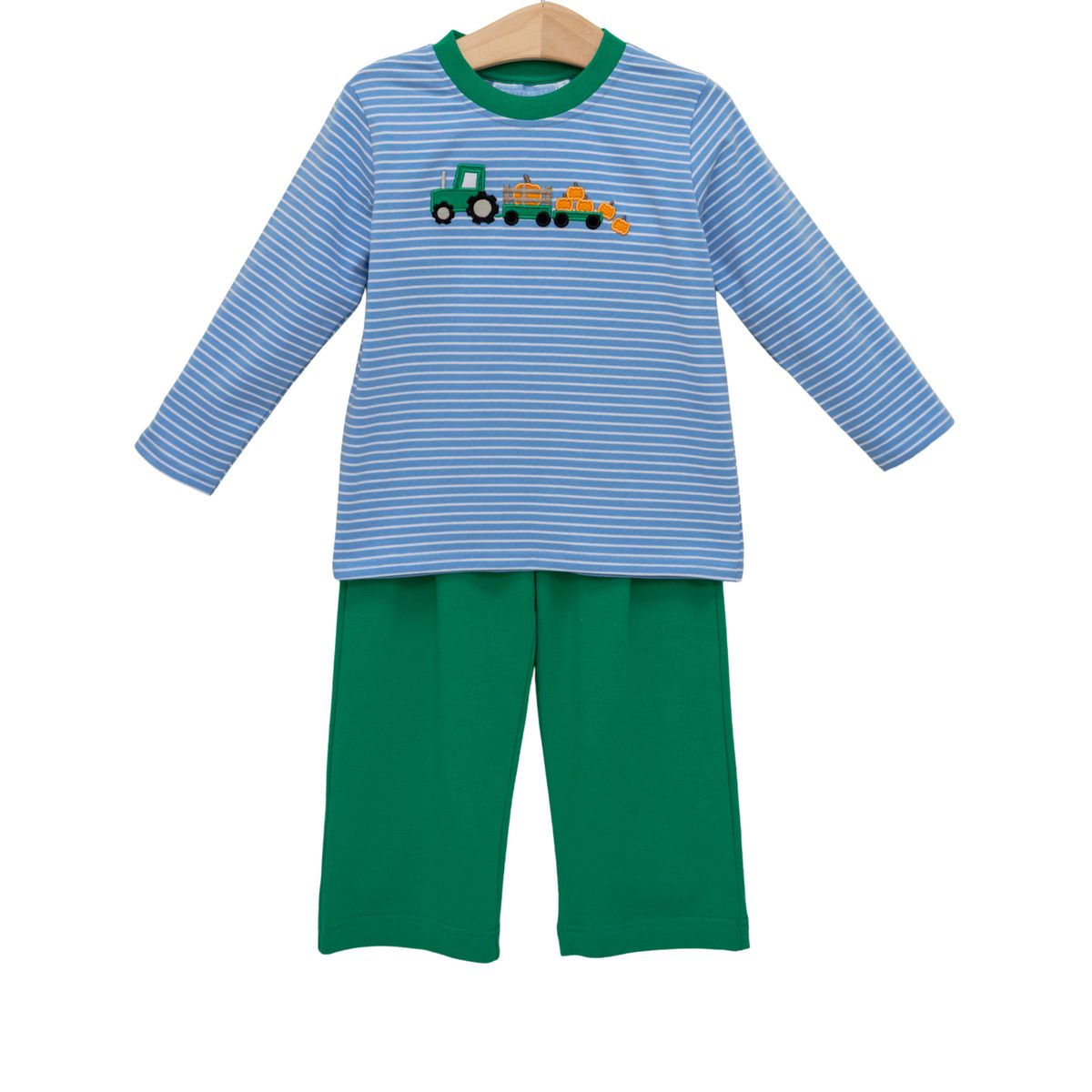 A two-piece children's long-sleeve pajama set on a wooden hanger, featuring a light blue and white striped top with a green tractor graphic, paired with solid green pants.
