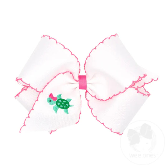 White hair bow with pink moonstitch edging and embroidered turtle.