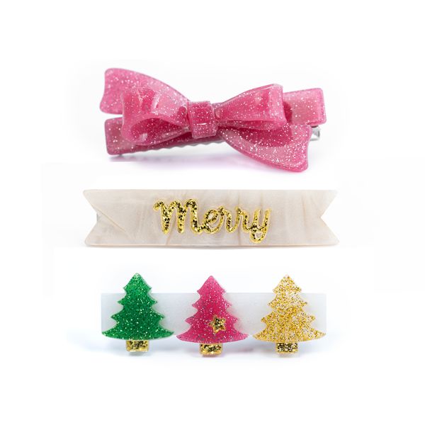 Three Christmas-themed hair clips on a white background: a pink glitter bow clip, a cream banner clip with glittery gold 'Merry' lettering, and a set of three glittery Christmas tree clips in green, pink, and gold.