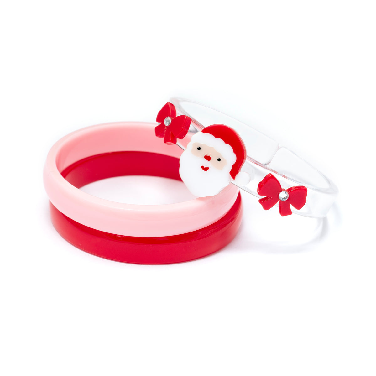 A set of three acrylic bracelets on a white background: a red ring, a light pink ring, and a clear ring decorated with a small Santa Claus face and red bows.